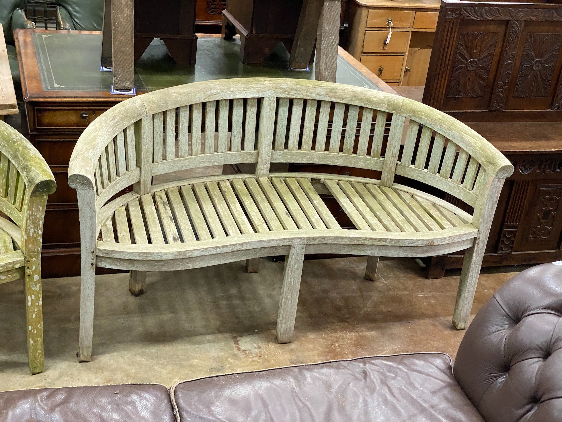 A pair of weathered teak 'banana' garden benches, length 158cm, depth 60cm, height 84cm (one with missing seat slat)